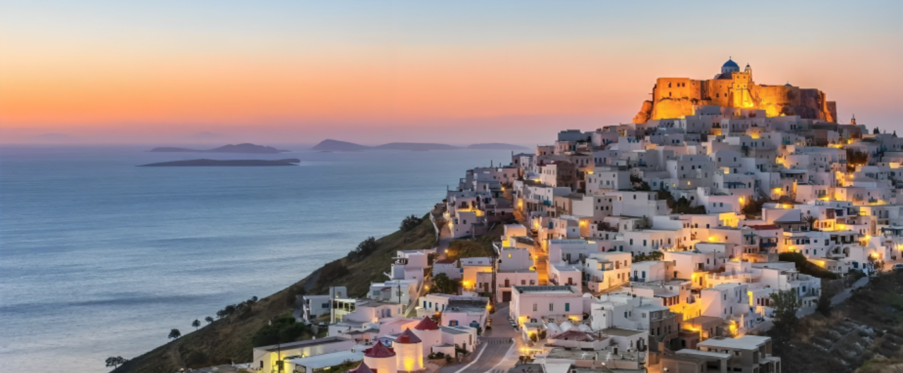 Hilltop village overlooking sea at sunset.