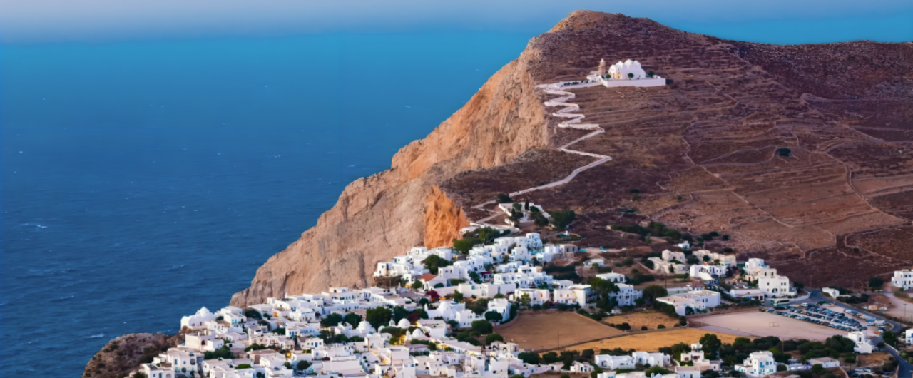 Coastal village with hillside path and sea.