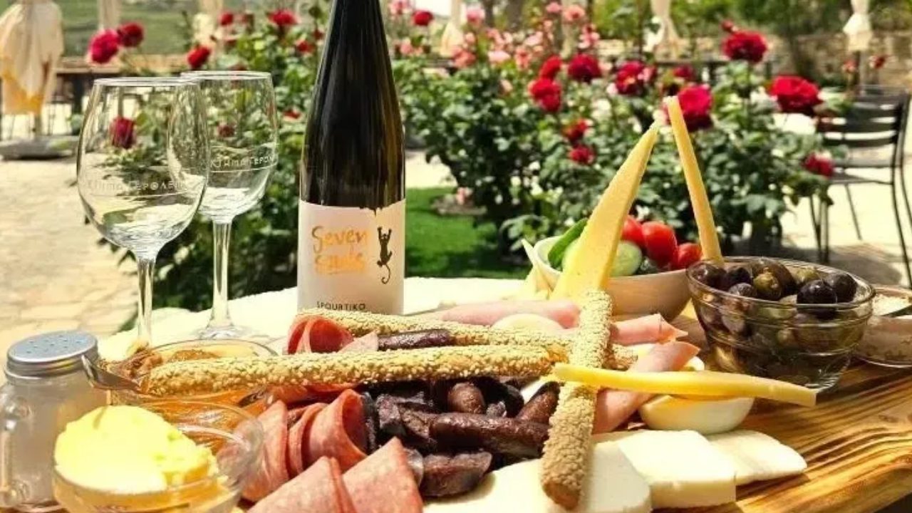 Charcuterie board with wine in garden setting.