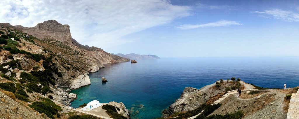 A serene coastal bay with calm blue waters and rocky cliffs.
