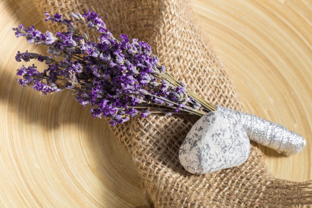 A bundle of dried lavender tied with twine on burlap and wood.