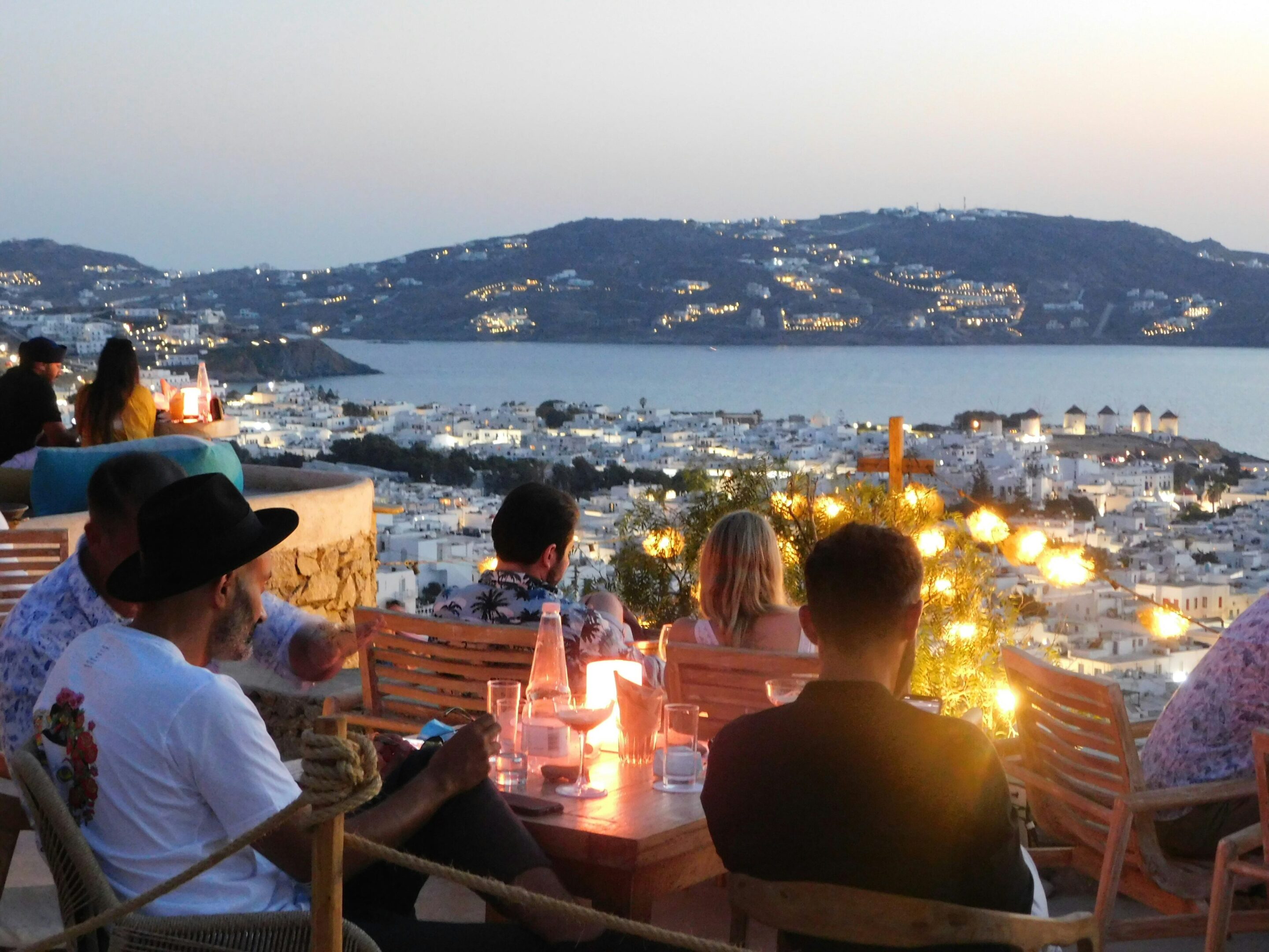 People enjoying a scenic evening with city lights and a waterfront view.