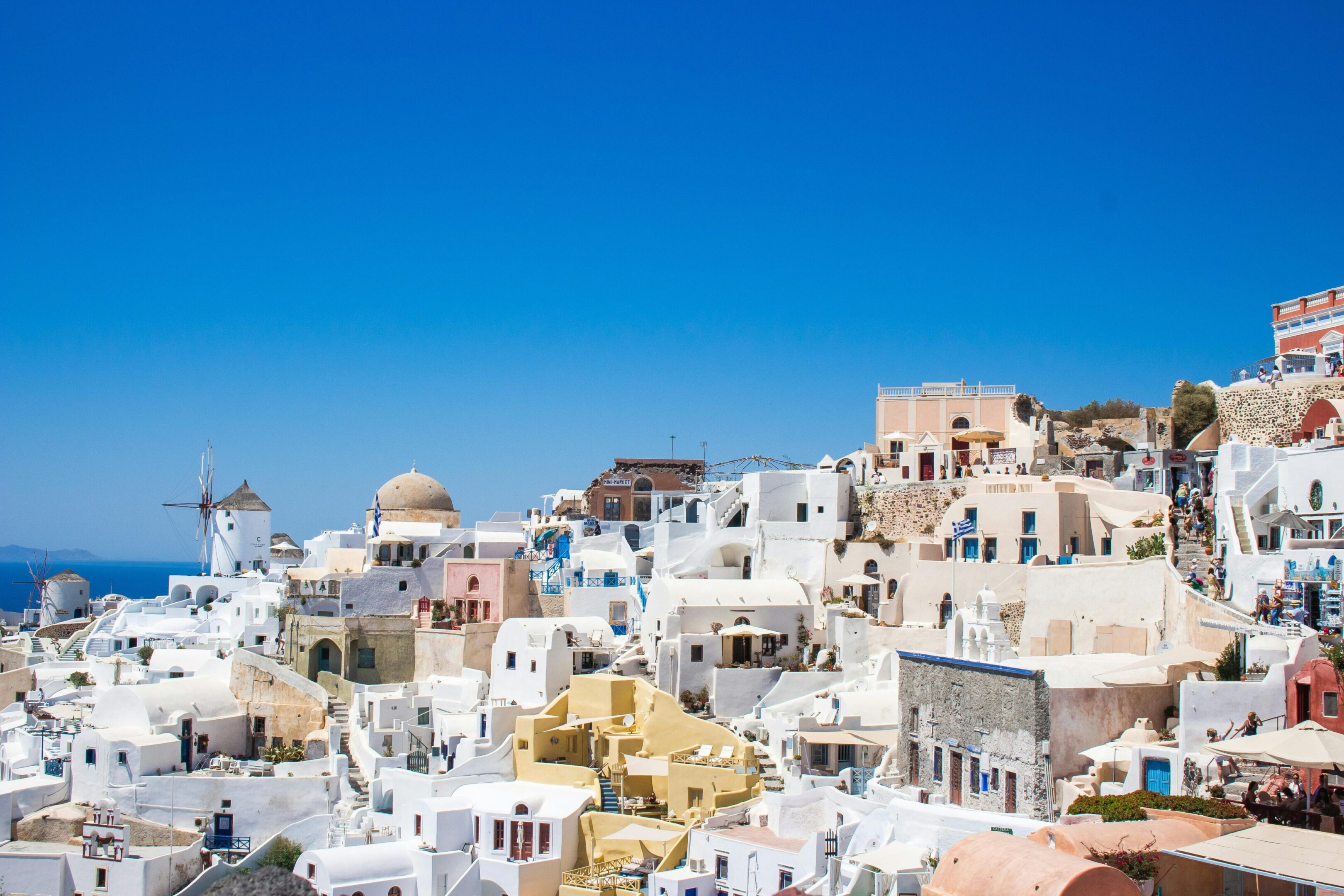 Scenic view of whitewashed buildings with blue domes under a clear blue sky.