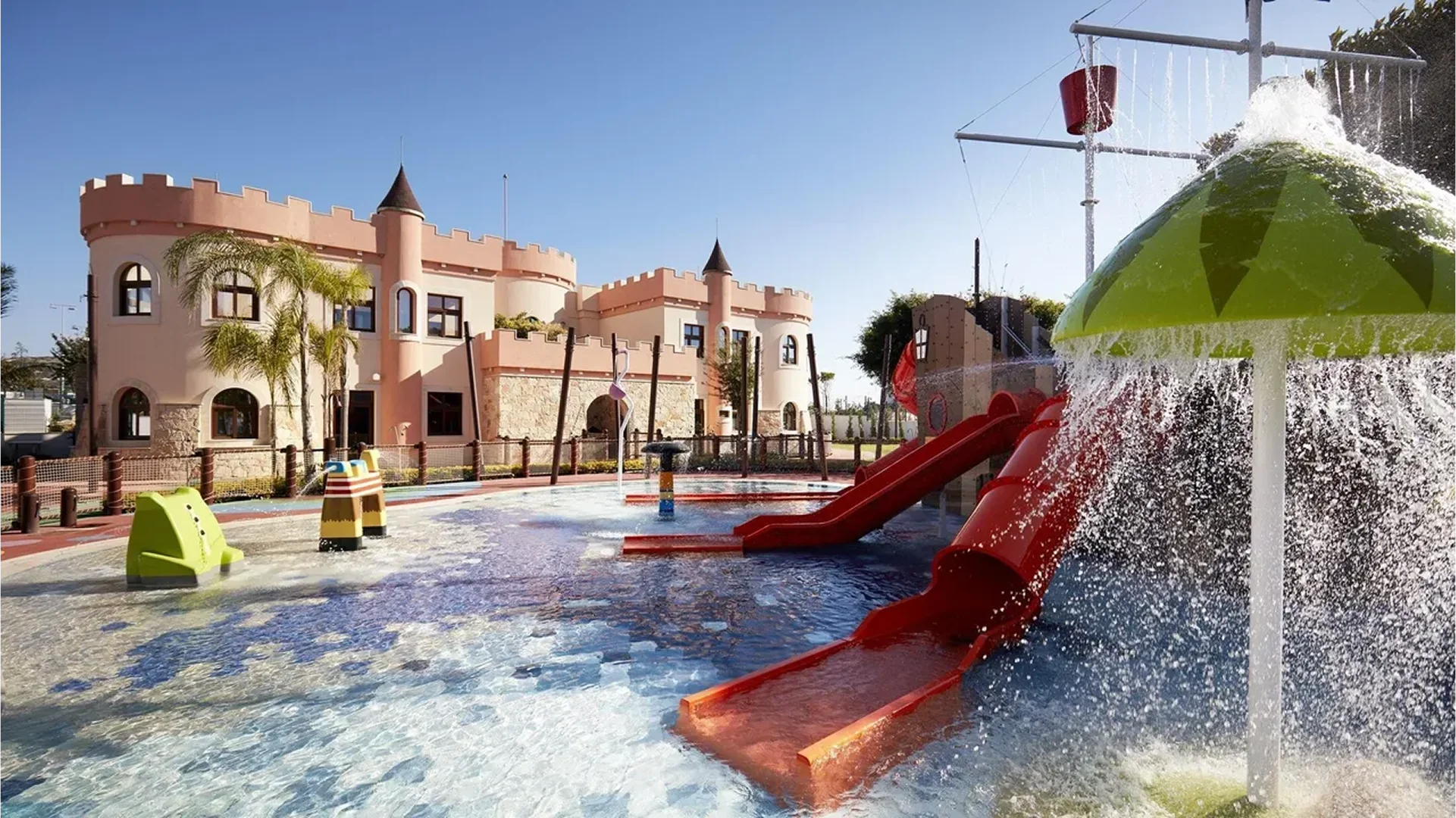 Water playground with slides and castle-themed structures under clear sky.