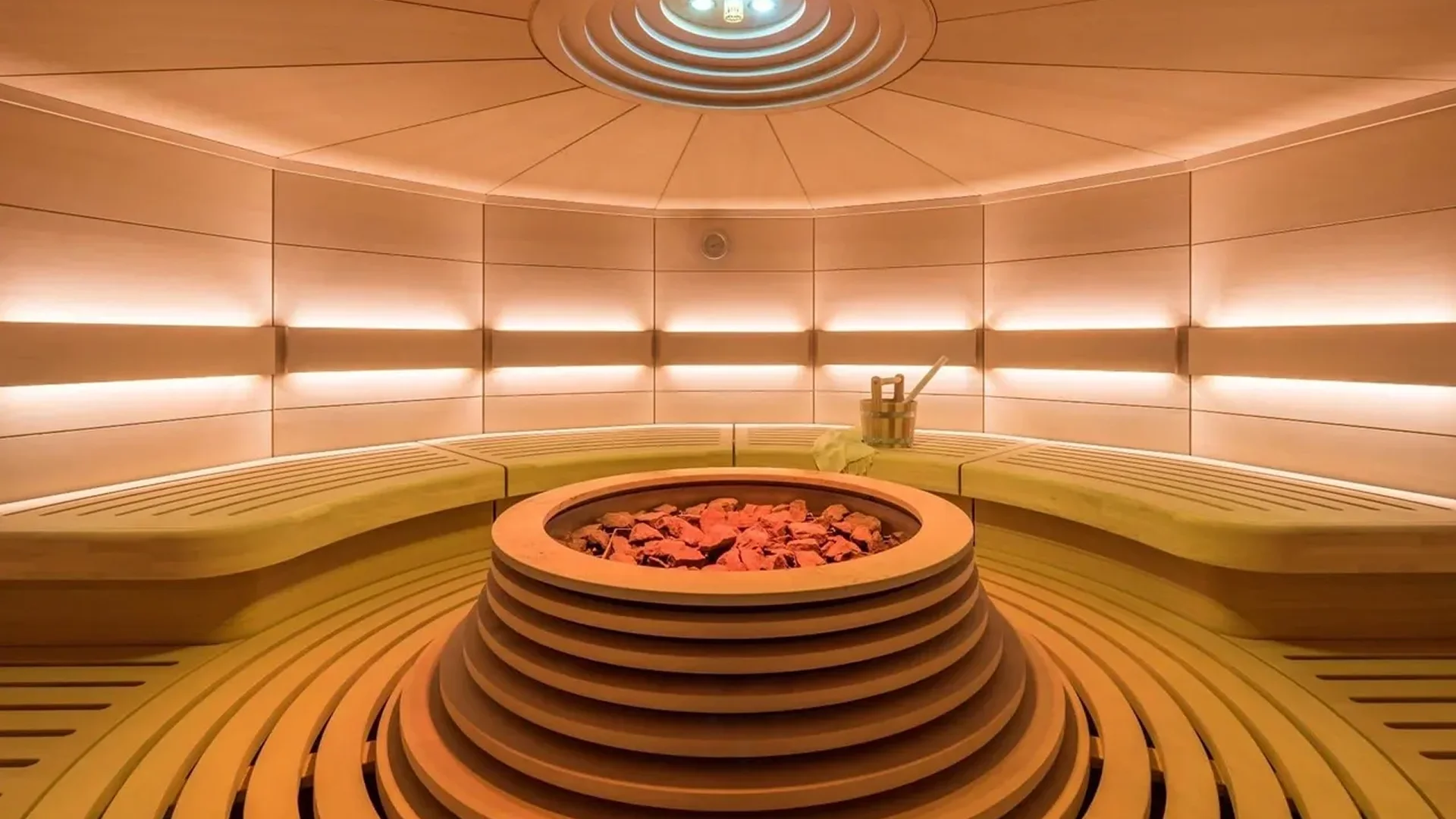 Luxurious sauna room with warm lighting and central stone heater.
