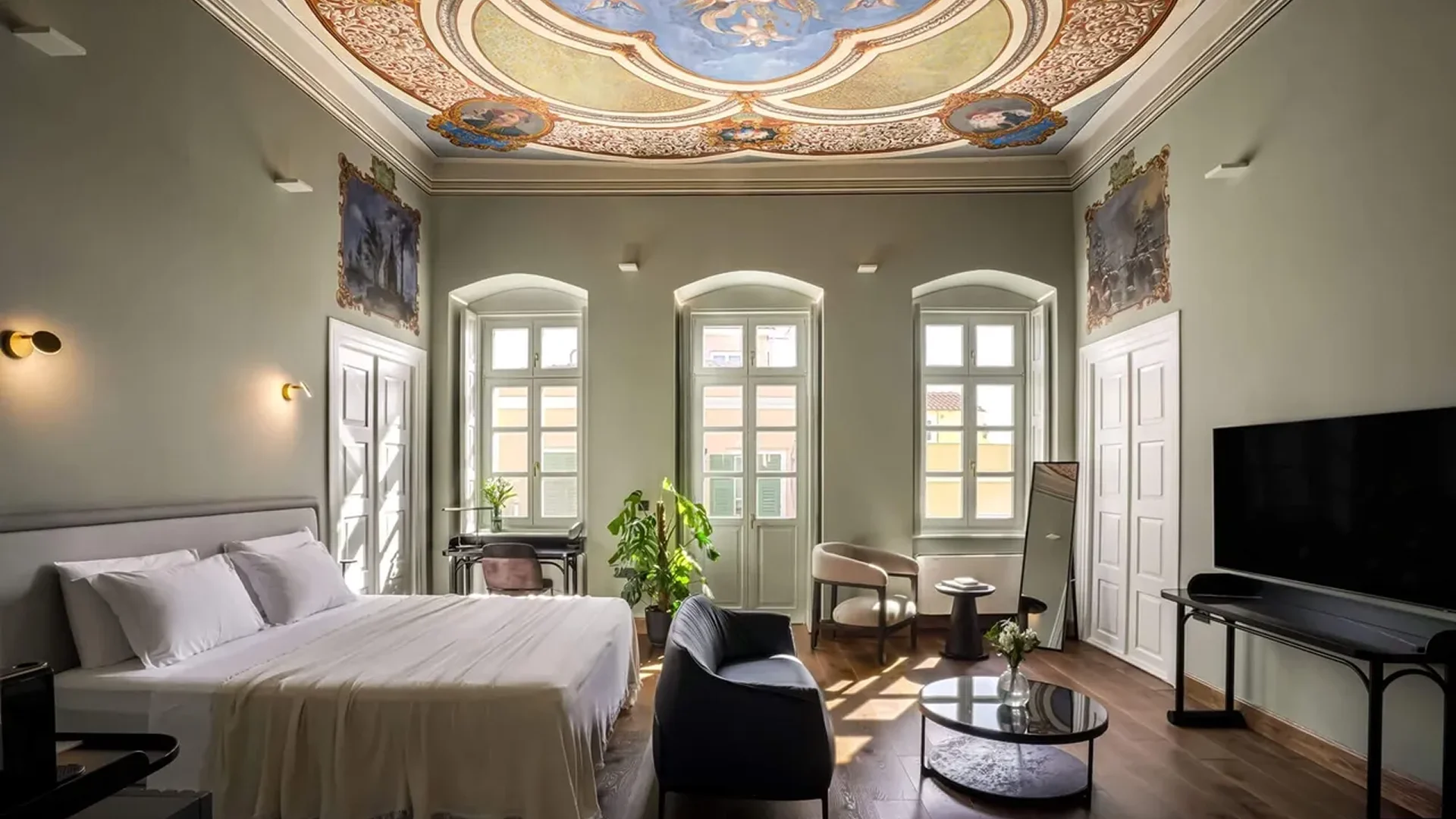 Elegant bedroom with ornate ceiling and large windows.
