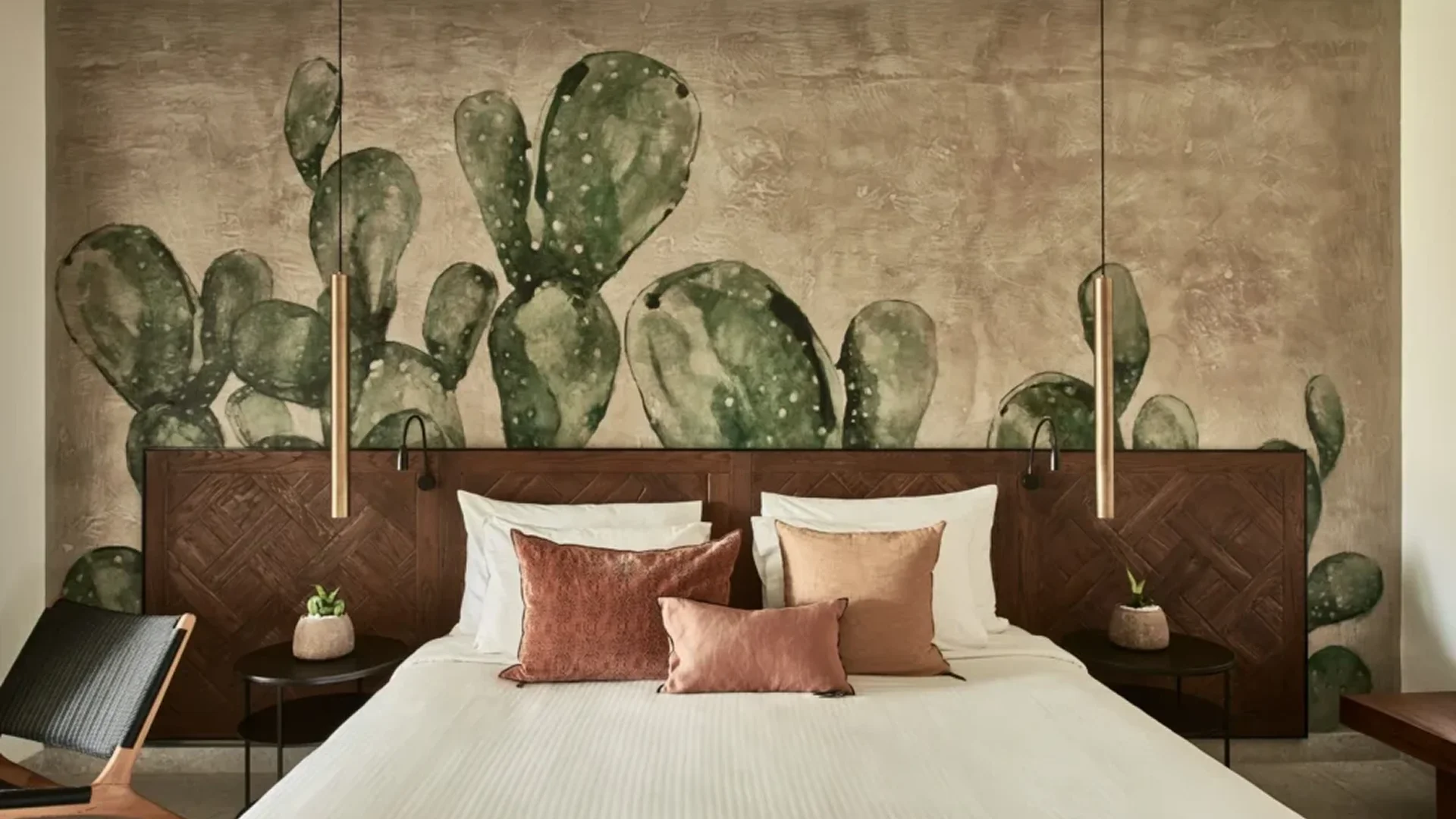 Cozy bedroom with cactus-themed wall art and warm-toned pillows.