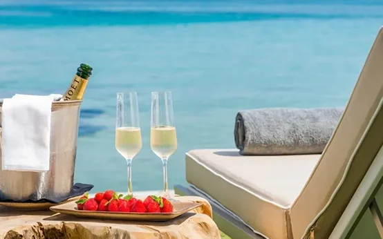 Champagne glasses, strawberries, and a poolside towel set for relaxation.