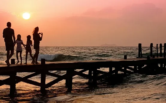 Silhouette of a person taking a photo on a pier at sunset.