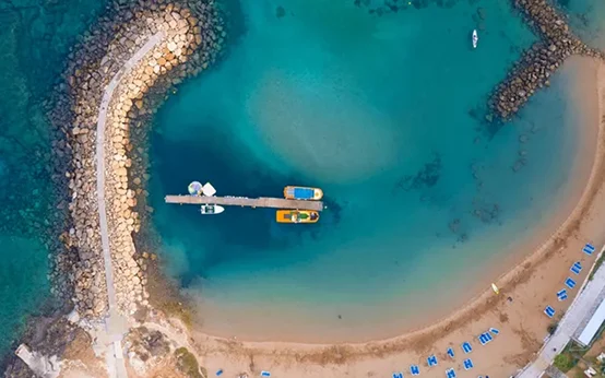 Aerial view of a pier extending into turquoise water with boats docked.