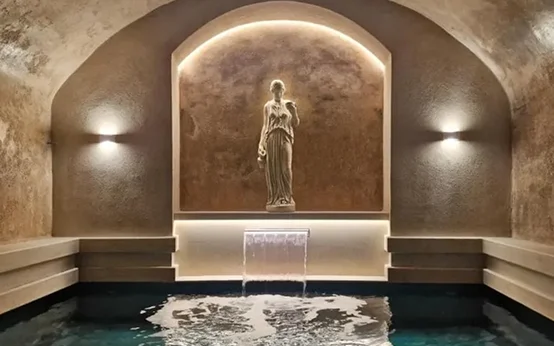 Elegant statue illuminated in a serene alcove above a reflective pool.