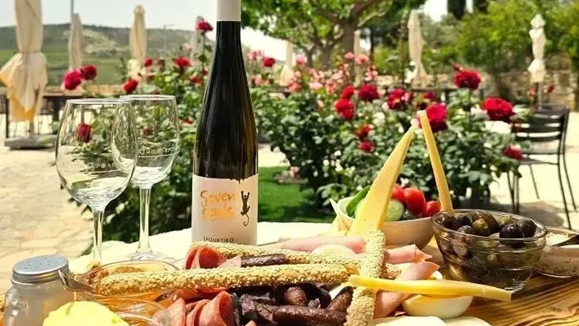 Wine bottle with charcuterie and fresh fruit on a wooden board.