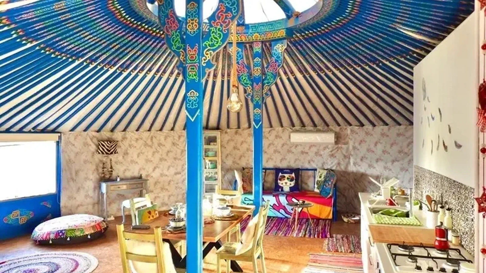 Colorful parrot sculptures hang in a cozy, artistic room with tables and chairs.