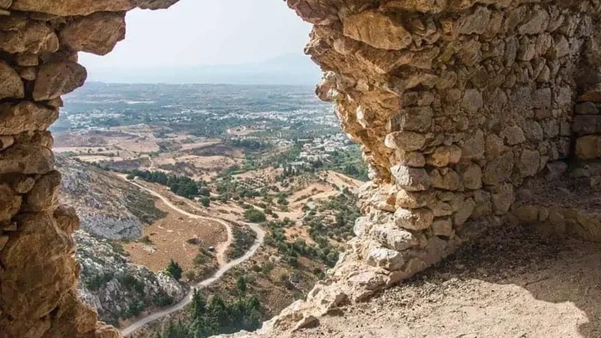 View from a rocky cliff overlooking a winding path and valley below.