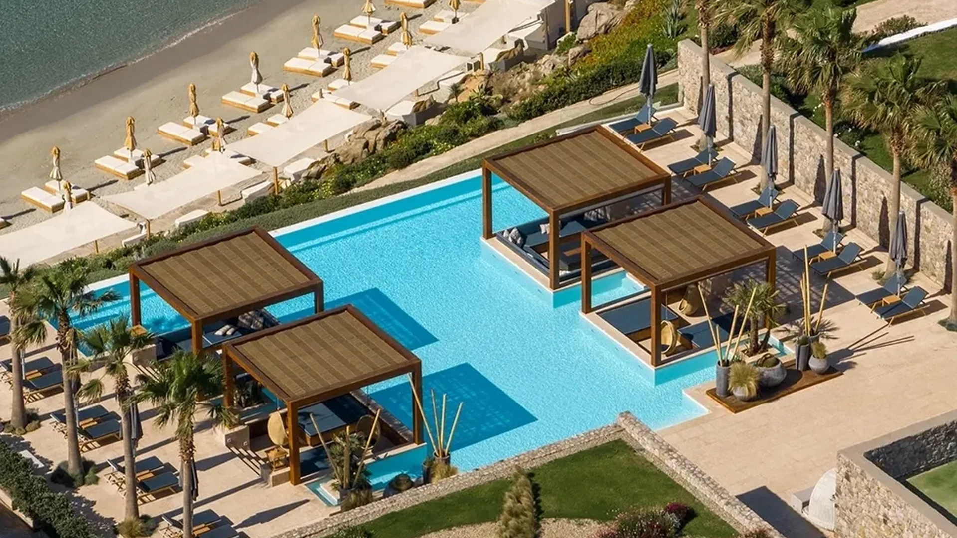 Luxury pool area with cabanas and lounge chairs by the beach.