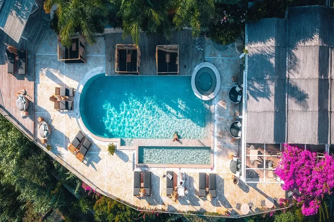 Aerial view of a modern pool area with lounge chairs and umbrellas.