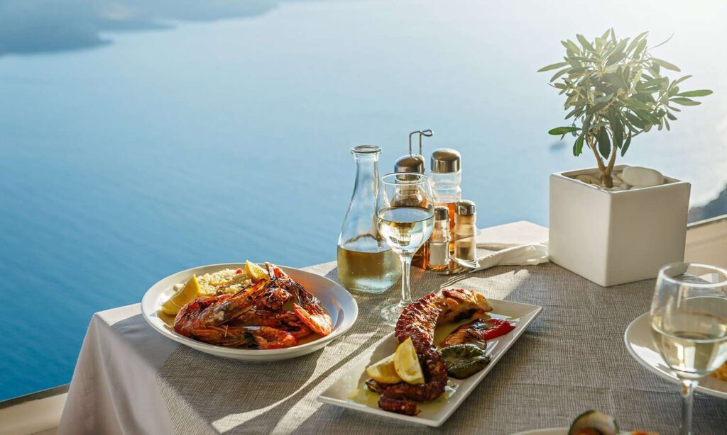 A seaside meal with seafood and drinks on a sunny patio.