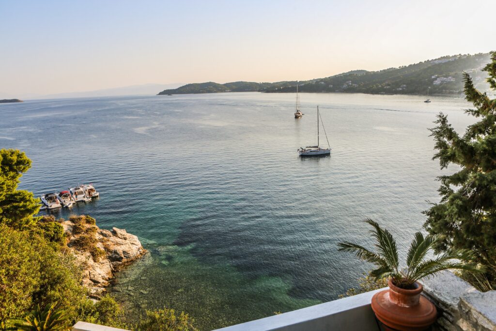 Sailboat anchored in calm coastal waters near rocky shore.