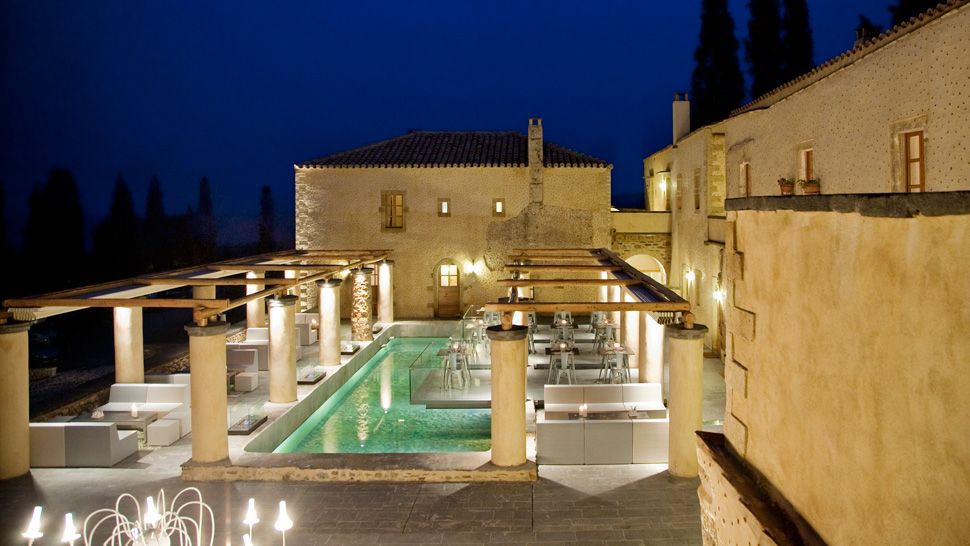 Elegant outdoor pool area at night with warm lighting and stone architecture.