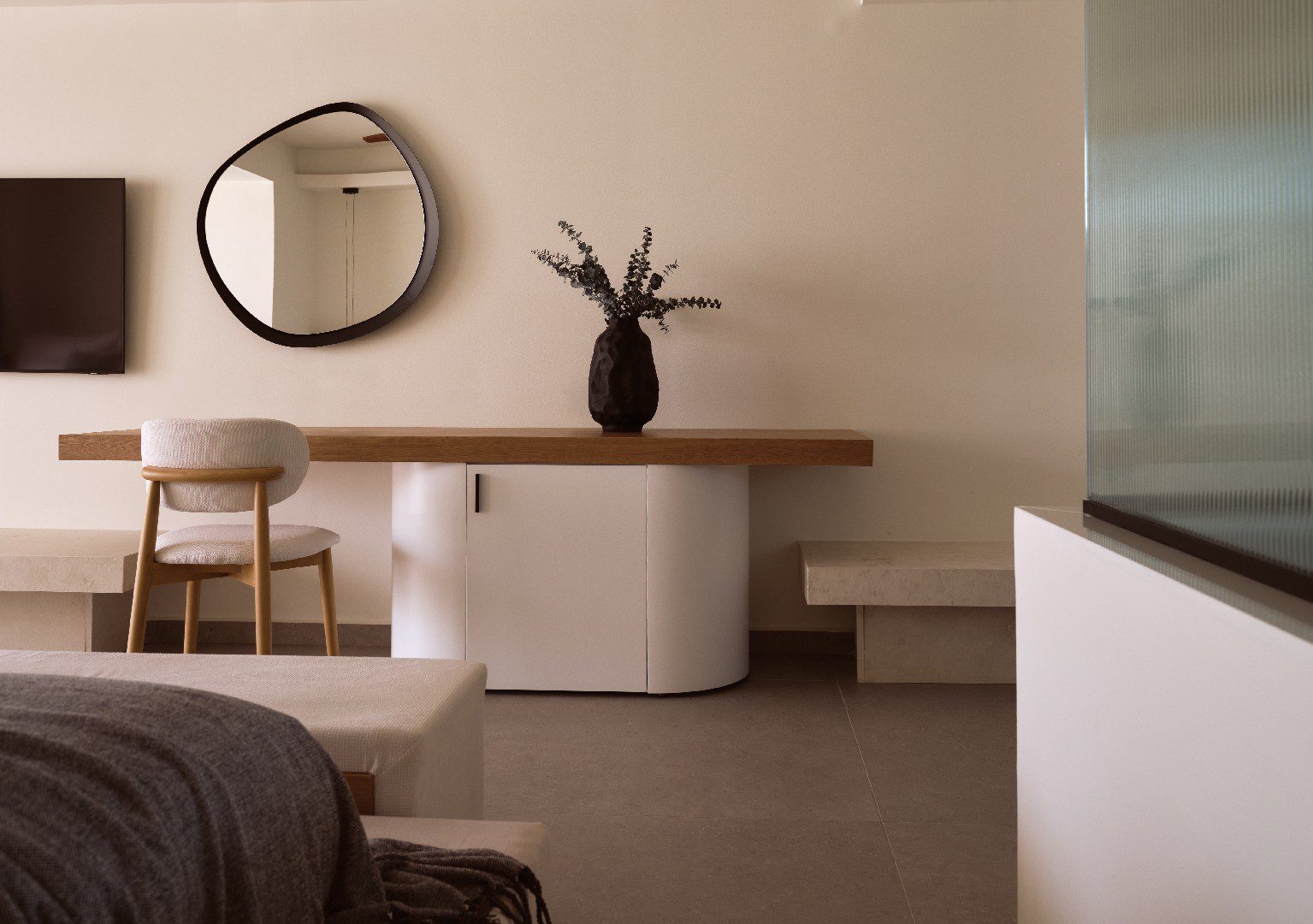 Minimalist room with a wooden table, round mirror, and simple decor.