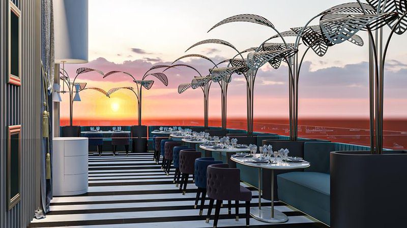 Elegant rooftop dining area overlooking a sunset-lit ocean.