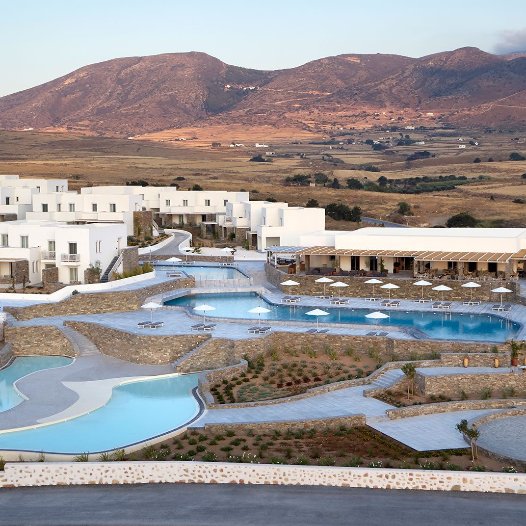 A luxurious resort with multiple pools set against a mountainous backdrop.