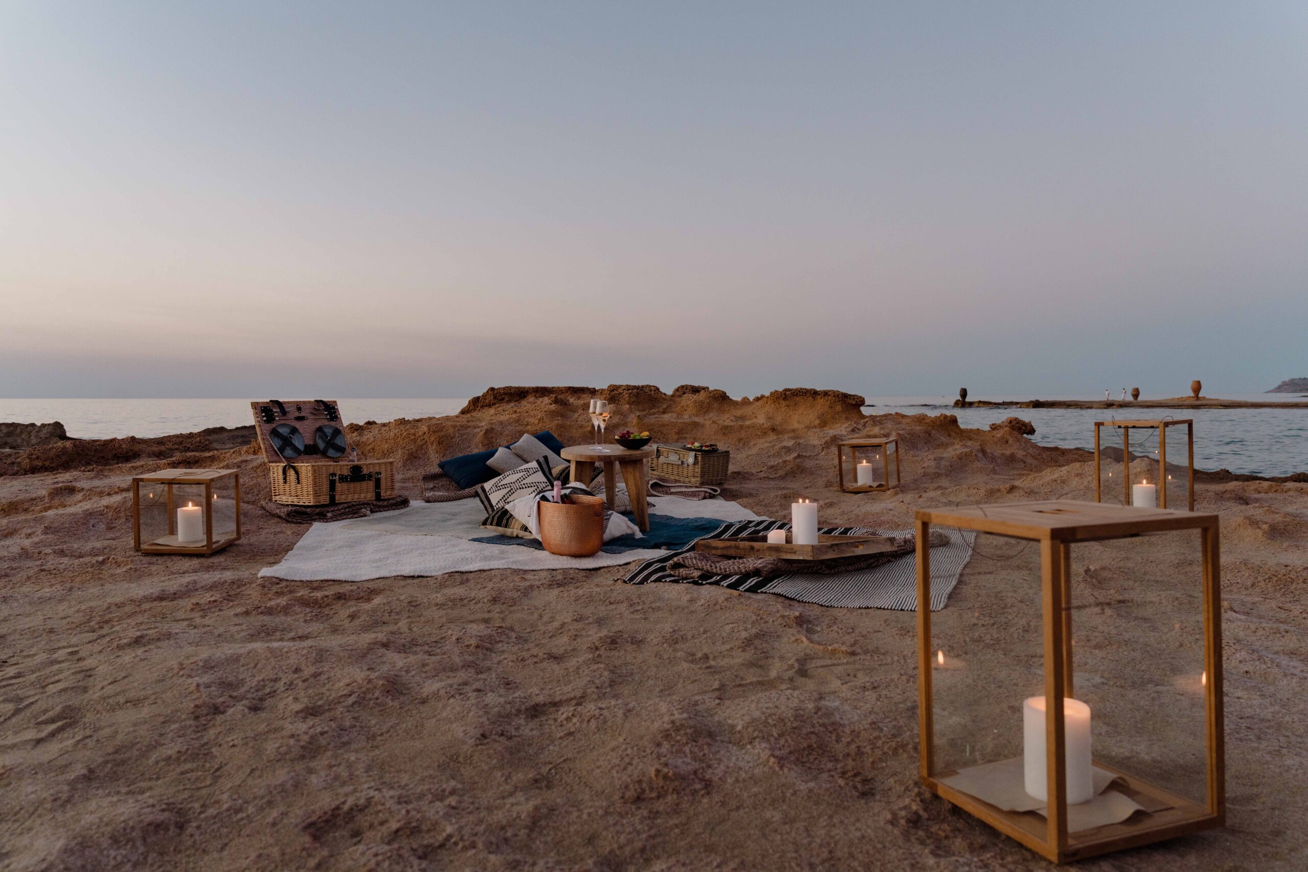 Cozy outdoor desert seating with cushions, lanterns, and a scenic sunset.