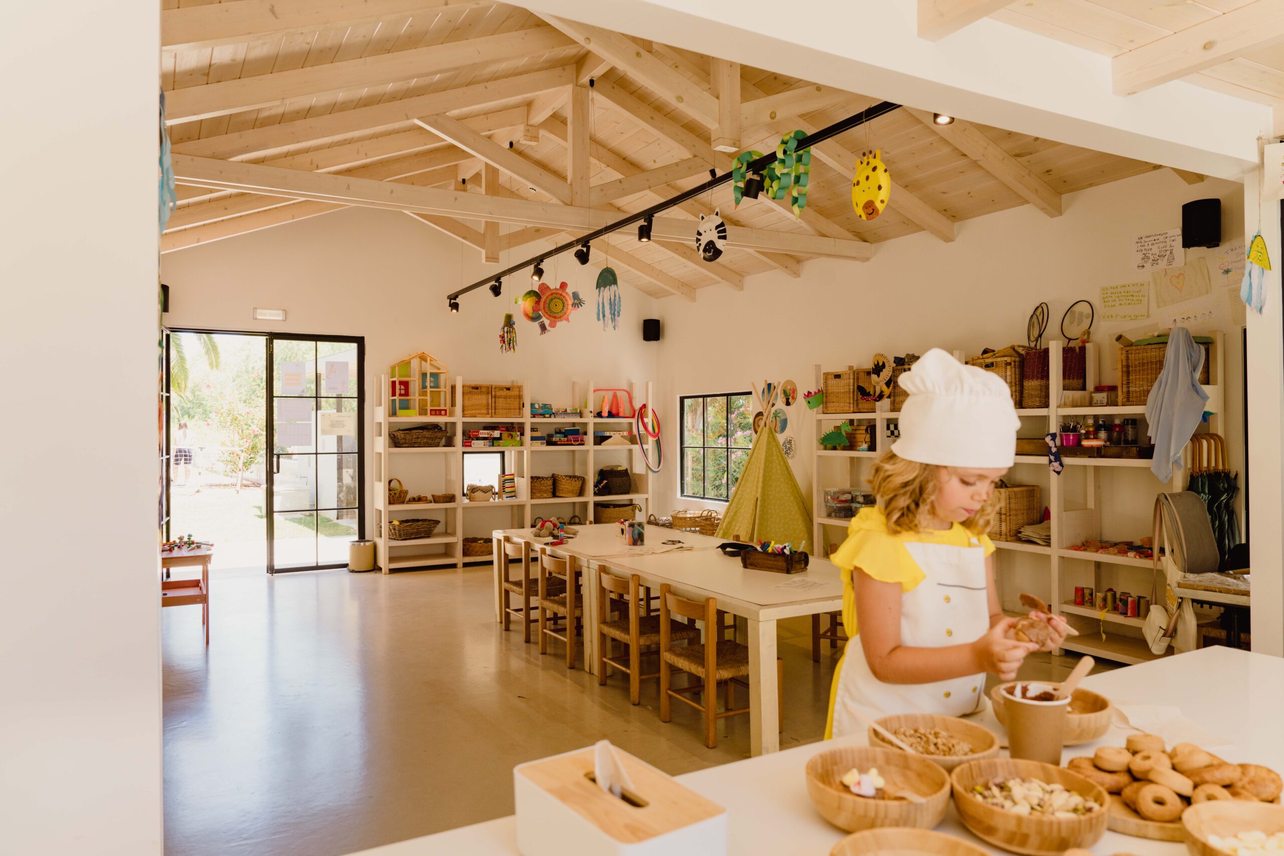 A child wearing a chef's hat prepares food in a bright, spacious kitchen.
