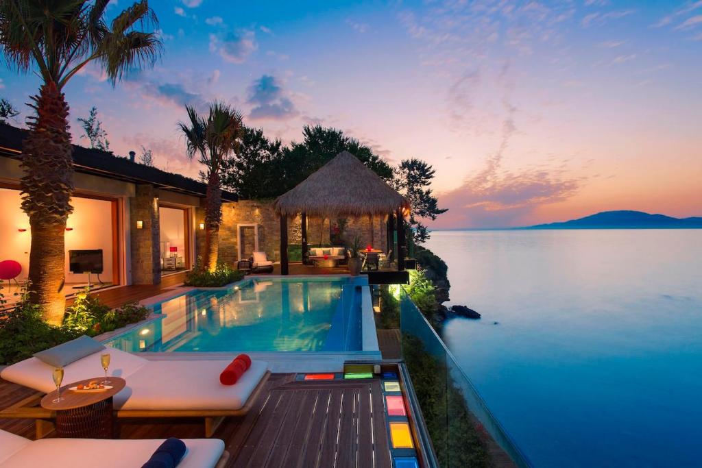 Luxurious infinity pool villa at sunset by the ocean.