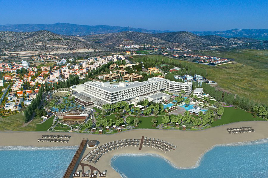 A large resort with pools by the beach and surrounding hills.