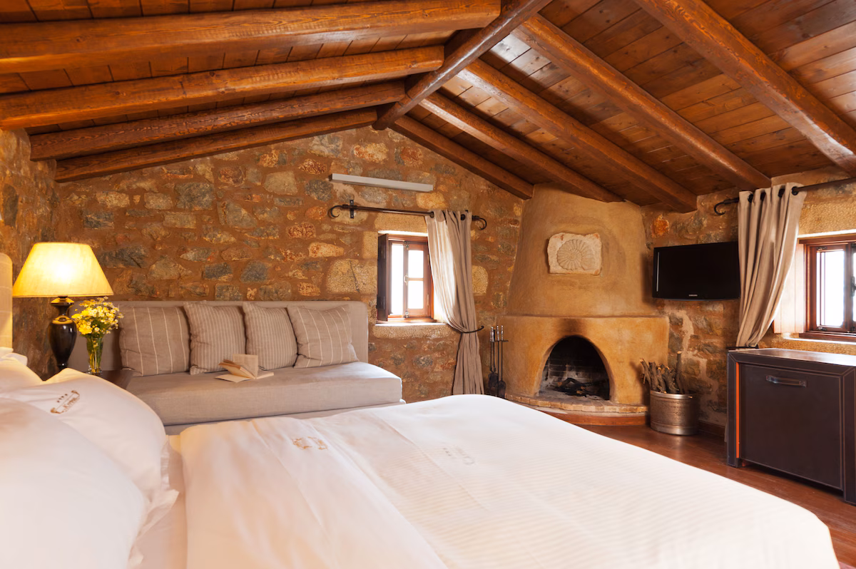 Cozy rustic bedroom with exposed wooden beams and stone walls.