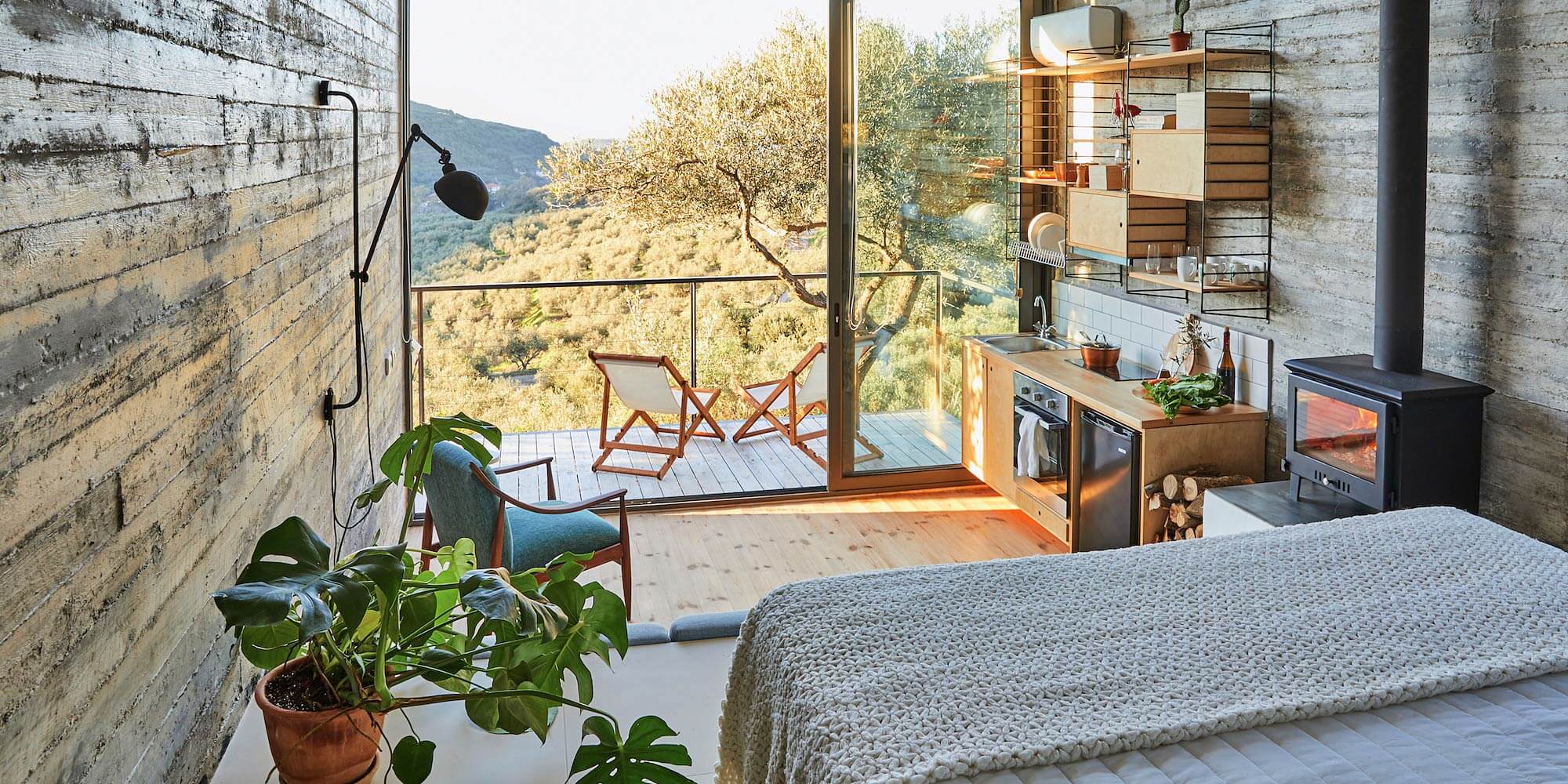 Cozy bedroom with large window and balcony overlooking trees.