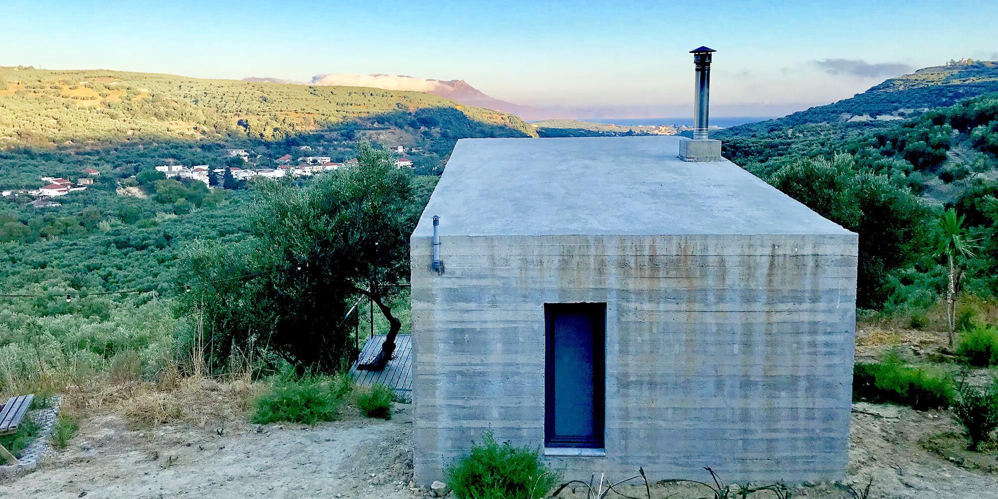 A modern concrete building with a chimney overlooking a scenic coastal landscape.