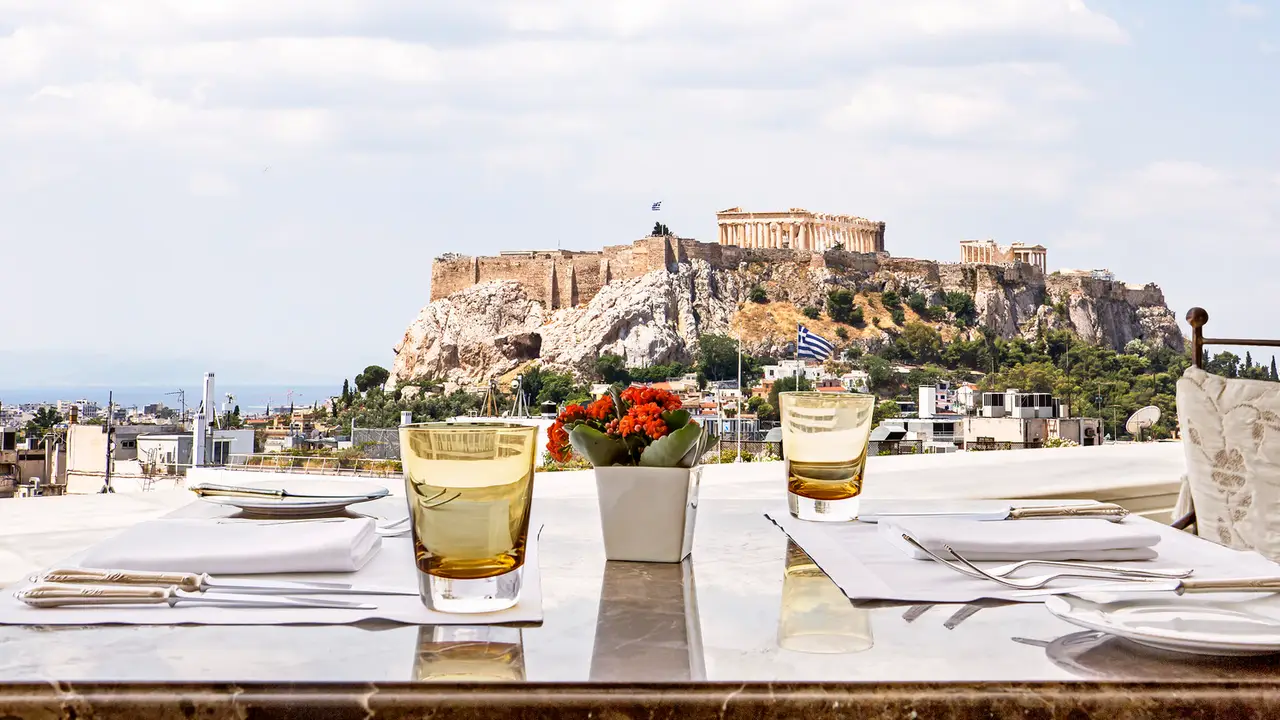 View of the Acropolis with glasses and flowers on a table in the foreground.