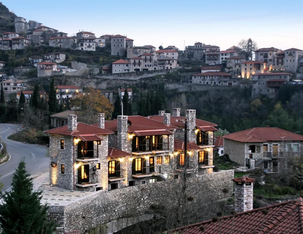 Luxurious stone villa with red roofs overlooking a hillside town at dusk.
