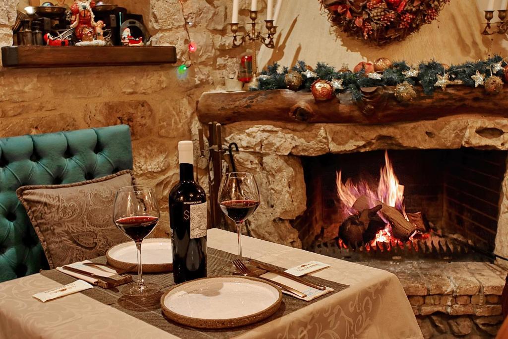 Cozy dining setup by a roaring fireplace with wine and Christmas decorations.
