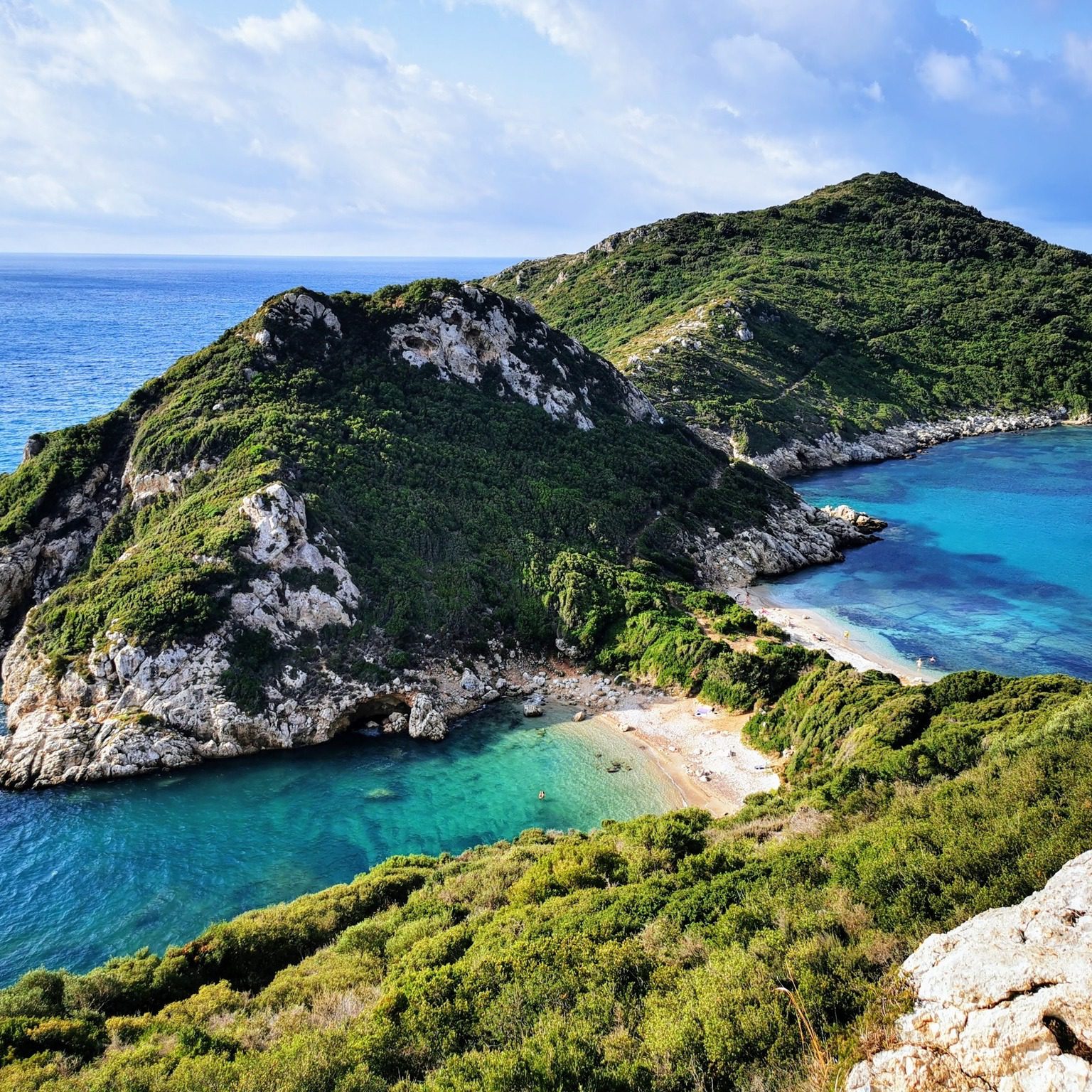 Scenic coastal view with lush green hills and turquoise waters.