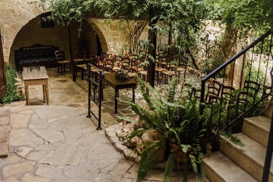 Cozy outdoor dining area with rustic stone walls and greenery.