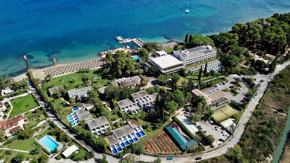Aerial view of a coastal resort with pools and tennis courts.