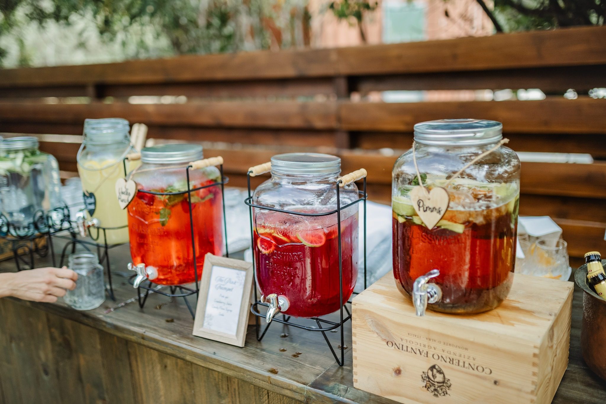 Jars filled with colorful infused waters and fresh herbs on a table.