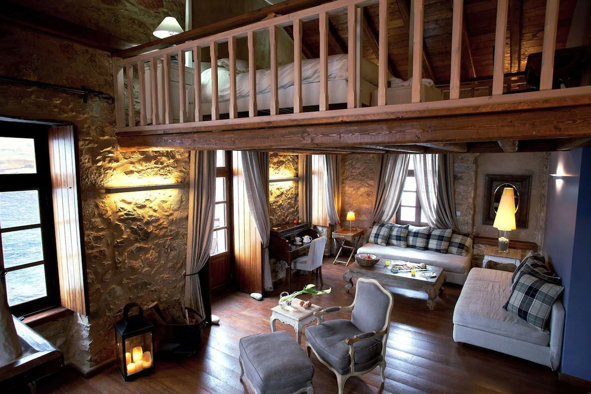 Cozy rustic living room with stone walls and wooden loft.