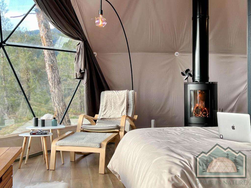 Cozy armchair with ottoman near a wood stove inside a tent.