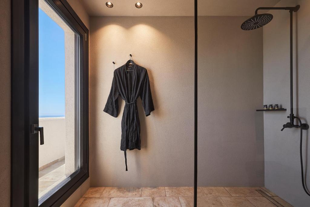 A black robe hanging on a wall in a minimalist bathroom.