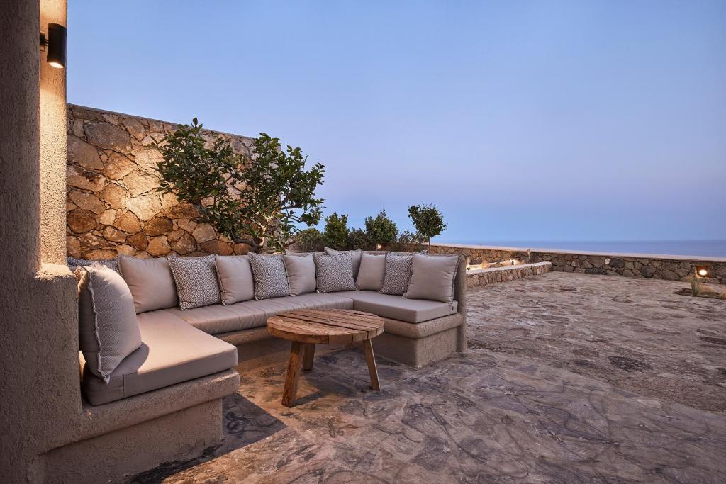Cozy outdoor stone patio with cushioned seating and wooden table under a clear evening sky.