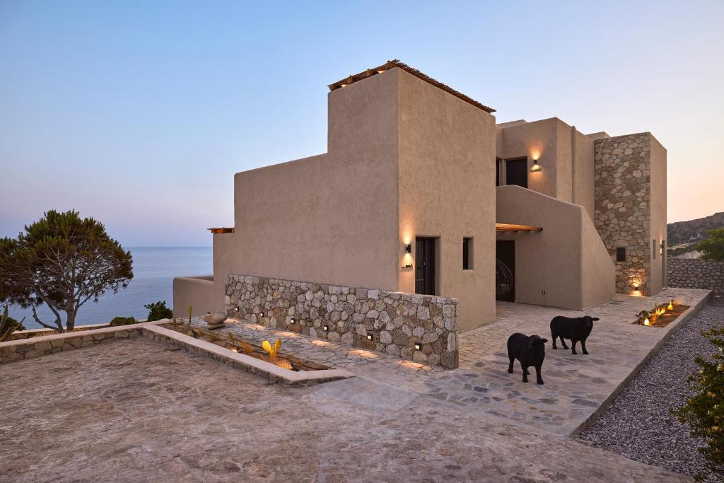 Modern desert home with stone wall and two black dogs at dusk.