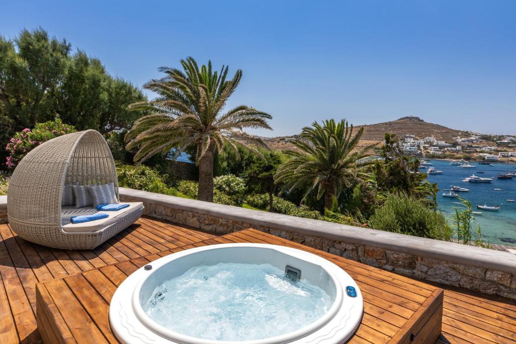 Outdoor jacuzzi on a wooden deck with palm trees and a scenic view.