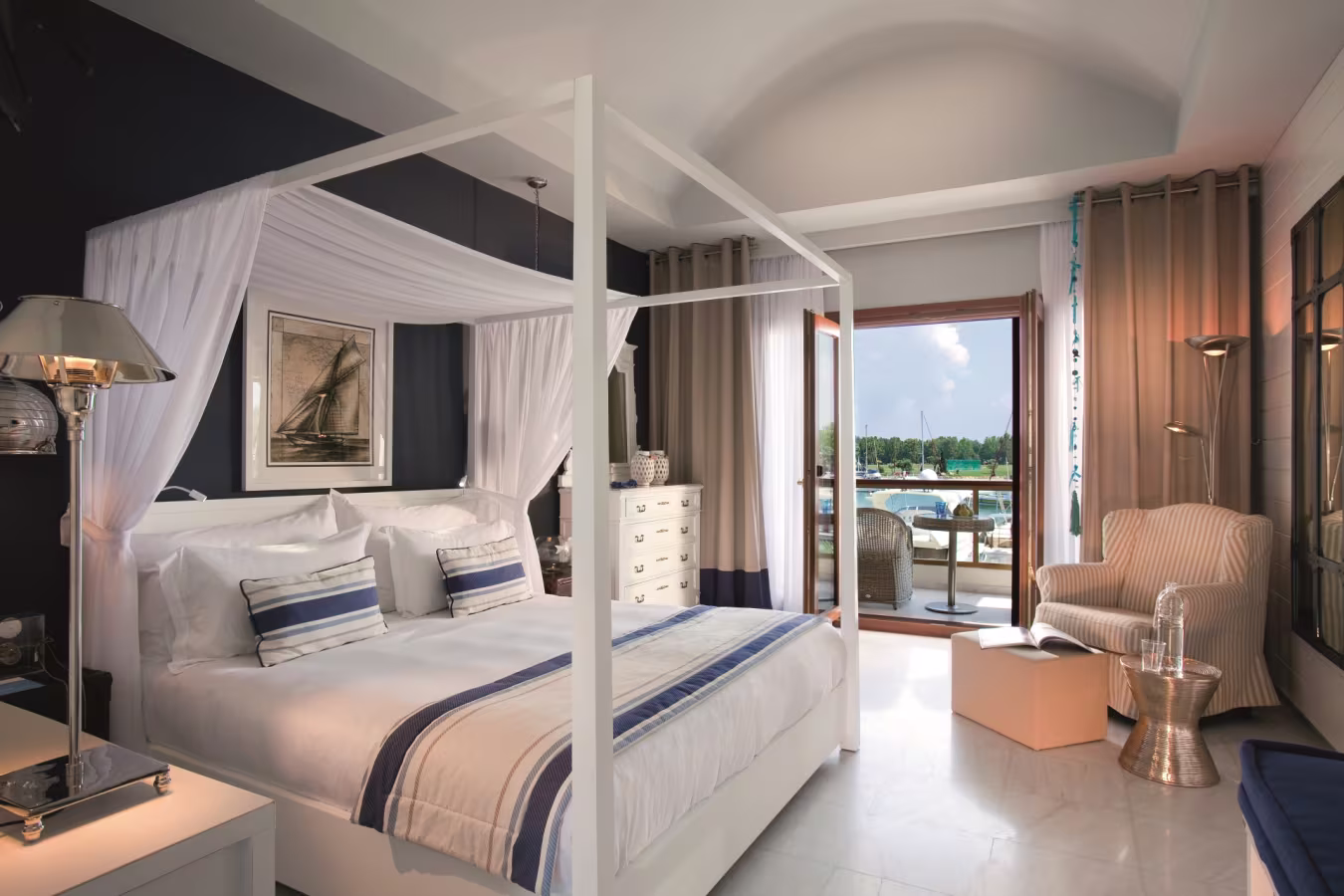 Elegant four-poster bed in a stylish room with ocean view balcony.