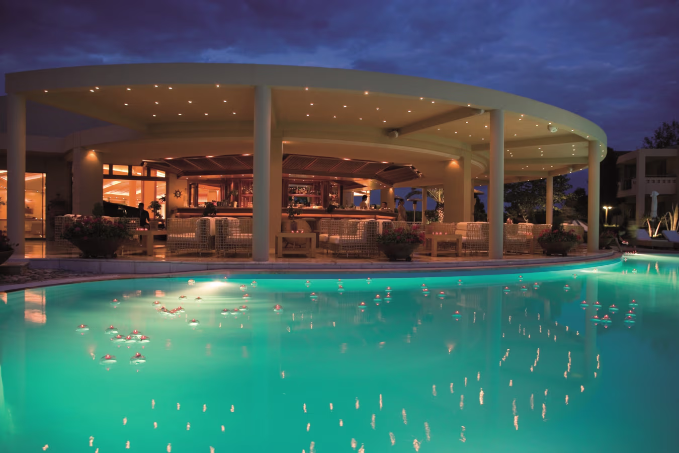 A luxurious poolside bar with ambient lighting at dusk.