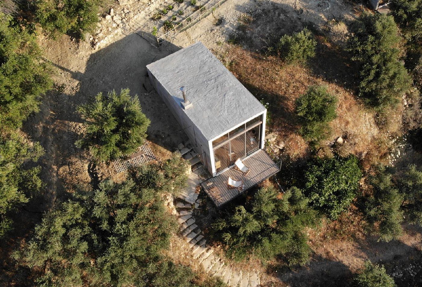 A small, rustic cabin surrounded by greenery and trees.