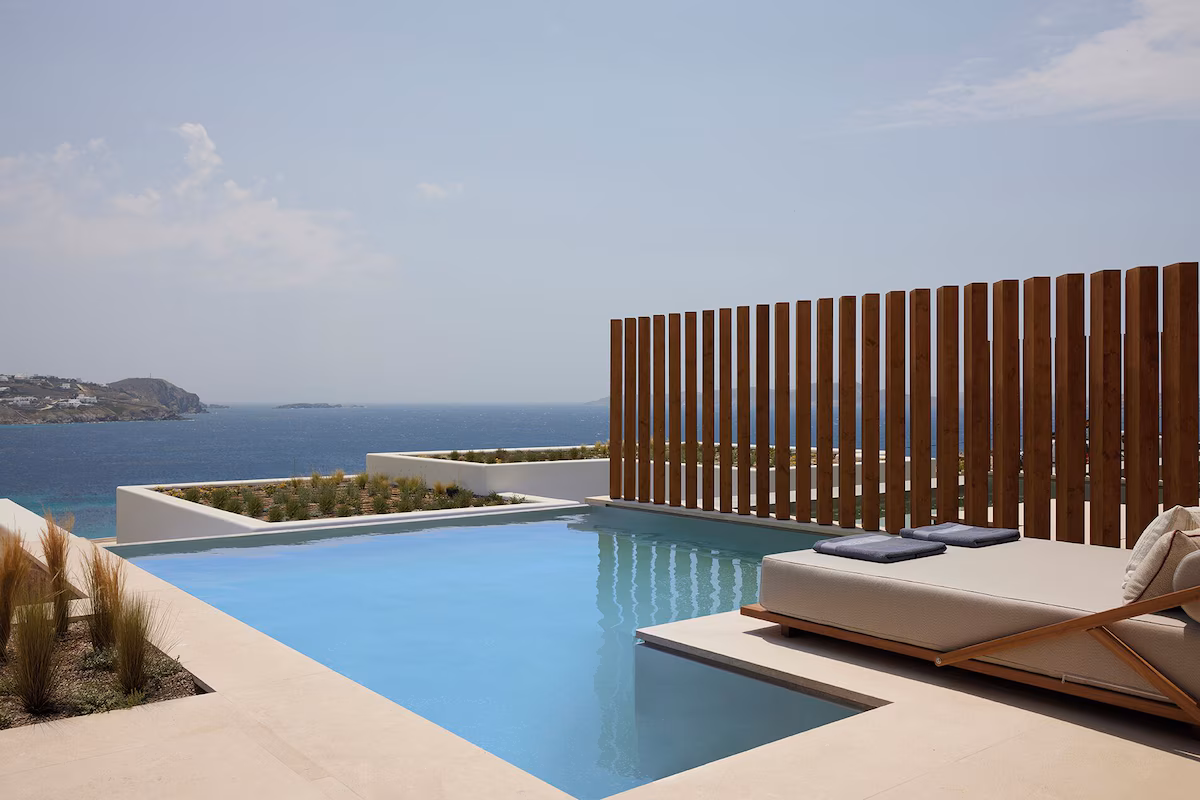 Infinity pool with sun loungers at Bill and Coo Mykonos capturing sunset over the Aegean
